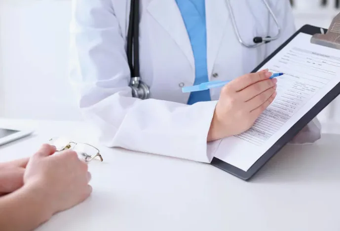 Doctor holding a clipboard while talking with a patient