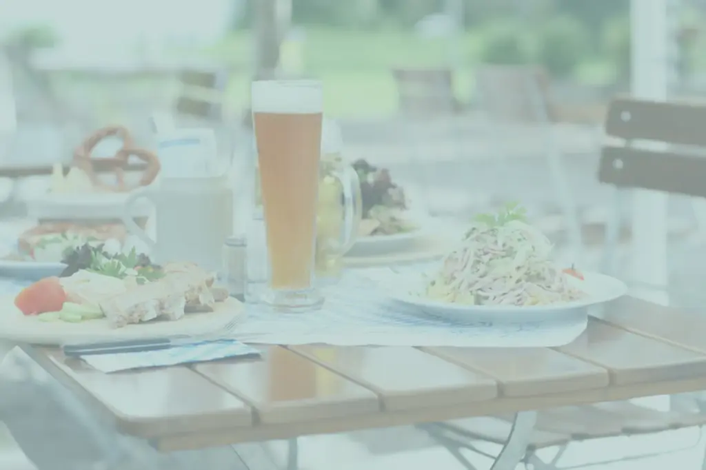 Glass of beer and plates of food on an outdoor table